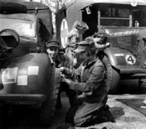 Elizabeth in overalls kneeling by the wheel of a truck