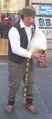 Serb bagpiper in traditional attire wearing opanci and šajkača.
