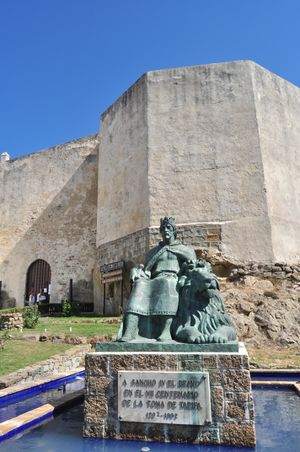 Statue of a sitting man outside a city wall