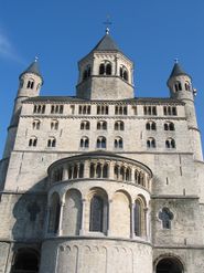 A tall rectangular structure of grey stone and stern appearance with a jutting apse and a small octagonal belfry.