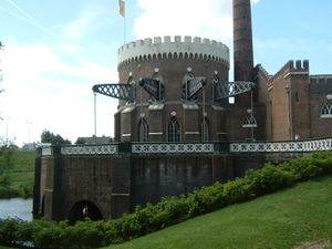 Round brick building of gothic architecture with steel beams protruding from the windows
