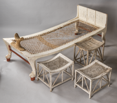 سرير مطلي باللون الأبيض يقف على أرجل أسد محاط بثلاثة مقاعد.