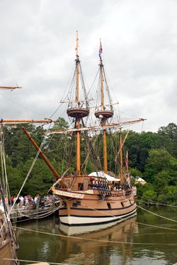 A sailing ship along a pier.
