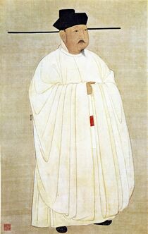 A man in heavy white robes, wearing a black hat with long horizontal protrusions coming from the bottom of the hat.