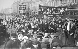 A large gathering of people outside, some holding banners