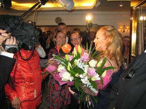 Ursula Andress in front of a crowd of people; a boom microphone is above her head