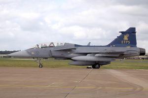 Grey and blue jet aircraft perpendicular to camera facing left, parked on ramp