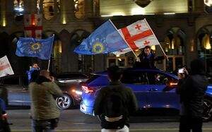 أحد أنصار حزب الحلم الجورجي الحاكم حاملاً علم الحزب وعلم جورجيا.jpg