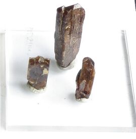 Three column shaped brown crystals on a white background