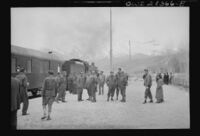 American and British Army train crewmen standing at a station. An American locomotive is seen at the head of the train at left. c. 1943