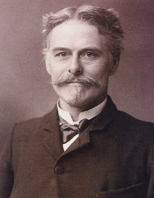 Head and shoulders of a middle-aged man who is looking at the viewer. He has a moustache and goatee, and his hair is short and parted in the middle. He is wearing a formal jacket, with a bow tie and wingless collar.