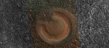 منظر قريب لبركان طيني كما تظهر بواسطة HiRISE. يبلغ عرض الصورة حوالي كيلومتر واحد. يختلف لون هذا البركان الطيني عن المناطق المحيطة به لأنه يتكون من مواد جُلبت من الأعماق. قد تكون هذه الهياكل مفيدة لاستكشاف بقايا الحياة الماضية لأنها تحتوي على عينات كانت محمية من الإشعاع القوي على السطح.