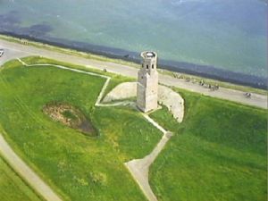 Arial photograph of a white stone tower near the shore