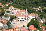 Aerial view of a castle with a white façade and orange roofs