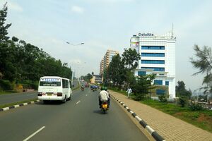 Photograph of a street, including buildings, vehicles and pedestrians