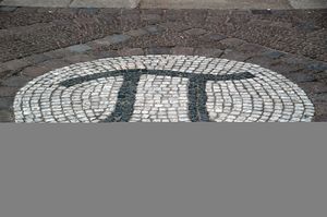 A photograph of the Greek letter pi, created as a large stone mosaic embedded in the ground.