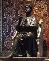 Peter is shown as a bearded man in draped garment like a toga. He is seated on a chair made of marble, and has his right hand raised in a gesture of blessing while in his left hand he holds two large keys. Behind the statue, the wall is patterned in mosaic to resemble red and gold brocade cloth.