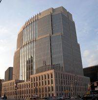 Exterior view of a tall beige building with many windows.