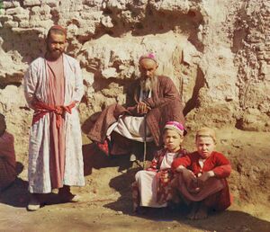 Two Sart men and two Sart boys posed outside, in front of wall, in the early 20th century.
