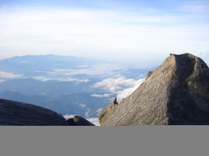 A view from Low's peak, with a smaller peak to the right of the photo, with forested mountains in the background