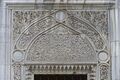 طبلة رخامية منحوتة بشكل معقد فوق نافذة خارجية للمسجد.