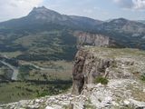 View of a scenic valley traversed by a narrow, swift watercourse from a large rock outcropping