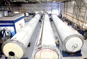 Long, cylindrical rocket sections lie in a warehouse