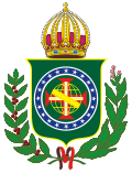 Coat of arms consisting of a shield with a green field with a golden armillary sphere superimposed on the red and white Cross of the Order of Christ, surrounded by a blue band with 20 silver stars; the bearers are two arms of a wreath, with a coffee branch on the left and a flowering tobacco branch on the right; and above the shield is an arched golden and jeweled crown.