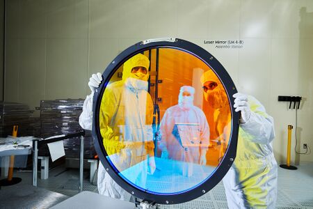 المهندسان البصريان جستين وولف (يسار) وسيمون كوهن مع مرشح r لكاميرا LSST.[130]