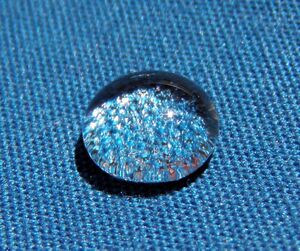 Shiny spherical drop of water on blue cloth
