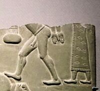 Man in patterned and fringed dress, behind naked prisoner.[8][5]